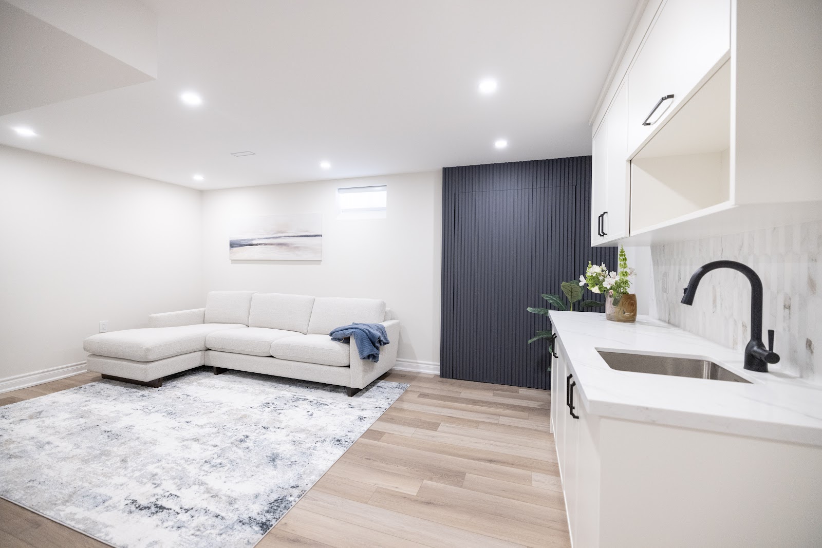 Basement wet bar with white quartz counter and kitchenette beside a lounge area, Hamilton