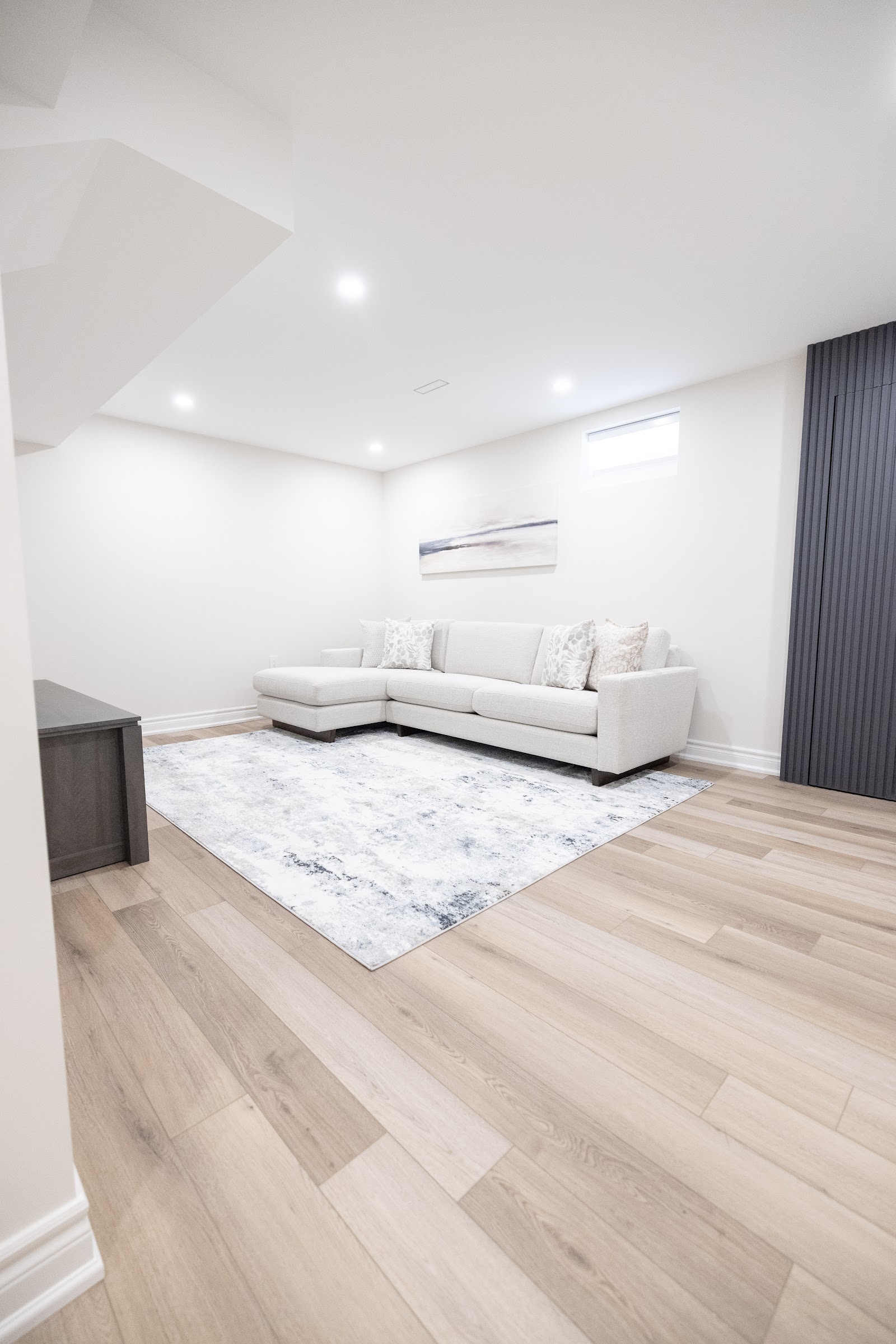 Bright finished basement living area with sectional sofa and pot lights, Hamilton renovation